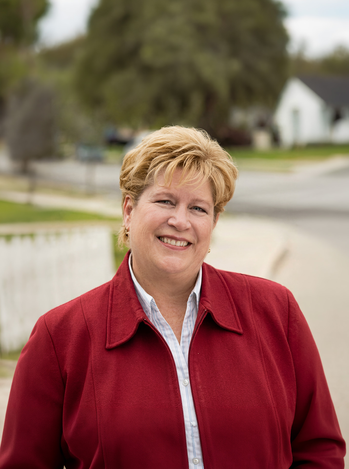 Cherryl Weaver, Northeast LA Realtor, smiling outdoors in a red jacket